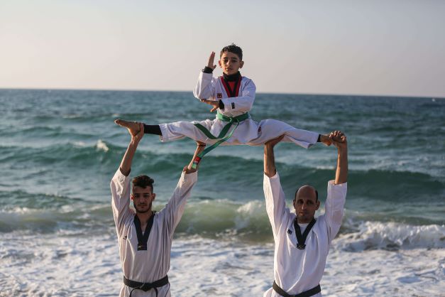 بالصور ؛ شبان وأطفال يمارسون رياضة التايكواندو على شاطئ بحر غزة