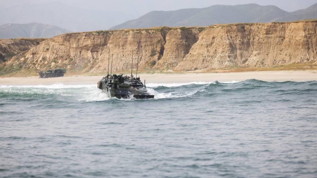 An Amphibious Combat Vehicle, with a TV mounted to its side, sits at the BAE Systems booth at the Sea-Air-Space conference in National Harbor, Maryland, in April 2023.