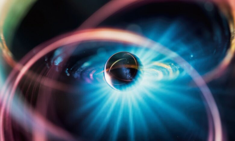 An illustration of a metal sphere surrounded by various colors and a glow of blue light.