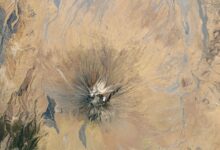 Satellite picture of a dry region with a volcano capped with white ash
